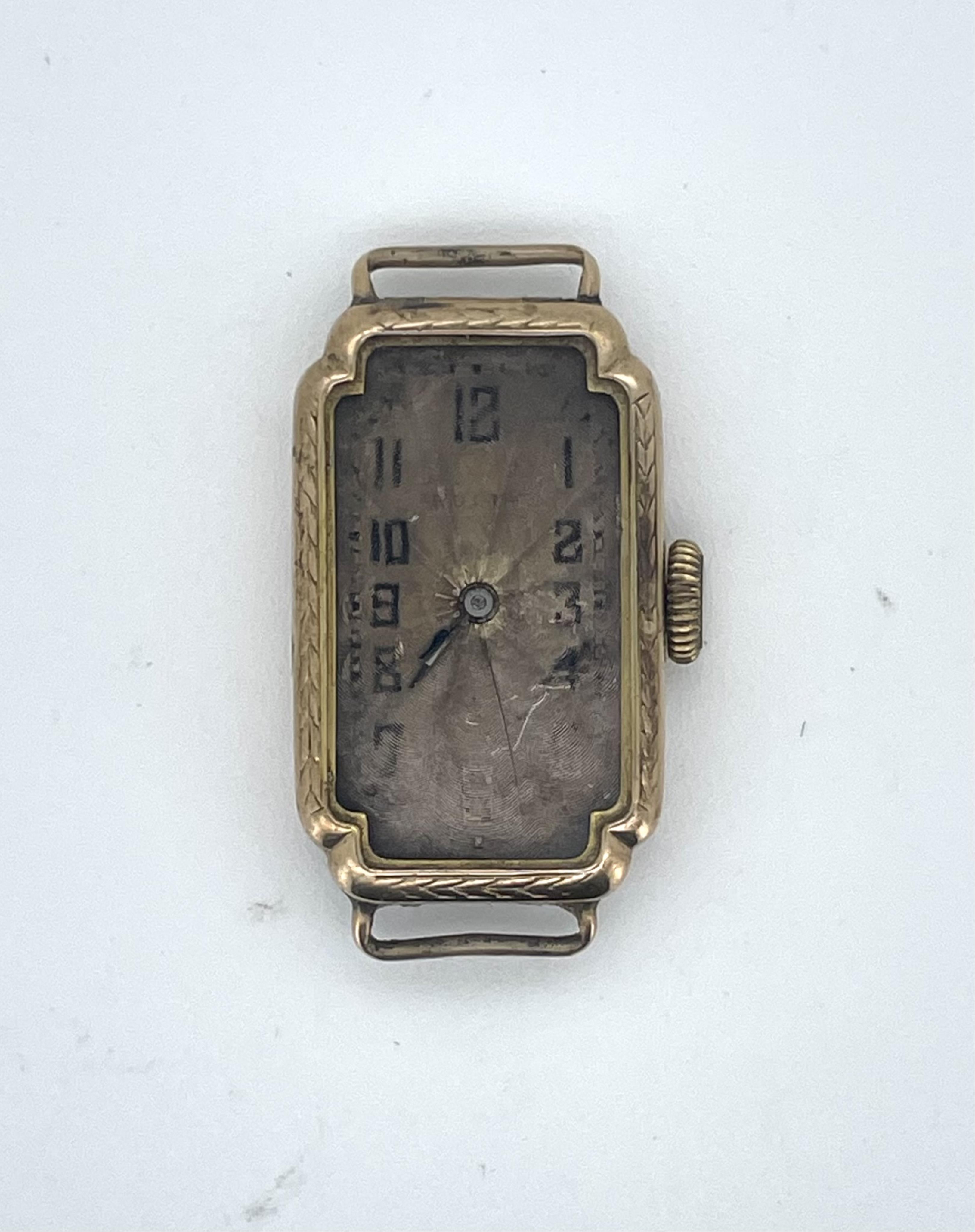 Rolex, a lady's 9ct watch, circa 1927, of elongated cross-shaped form, the guilloché dial with Arabic numeral indicators, to a gold case engraved with bands of laurel leaves, length 2.6 x 1.7cm including dial, reverse in